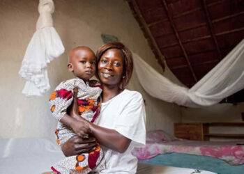 Insecticide-treated mosquito net behind mother and child