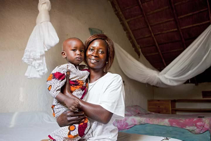 Insecticide-treated mosquito net behind mother and child