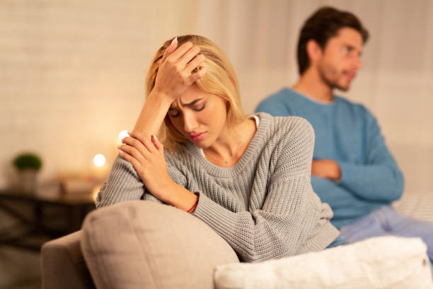 A unhappy woman sitting with her boyfriend with her hand on her face.