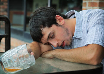 Man sleeping while holding a glass cup