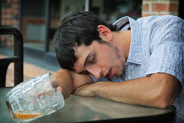Man sleeping while holding a glass cup