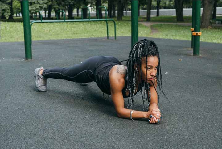 Young woman doing planks in dreadlock