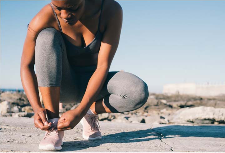 Beautiful young woman tying her shoes before going for a run