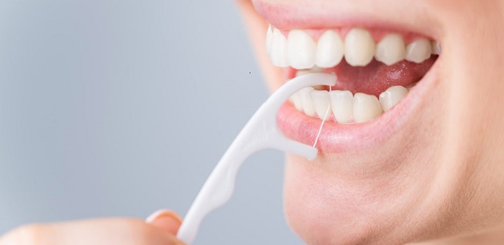 Plastic dental floss pick being used on the teeth