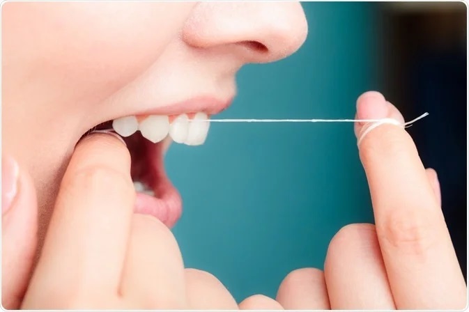 Stringed dental floss being used by a white woman