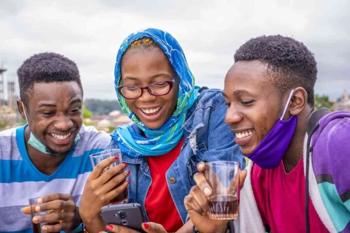 Nigerian youths smiling while watching their phone