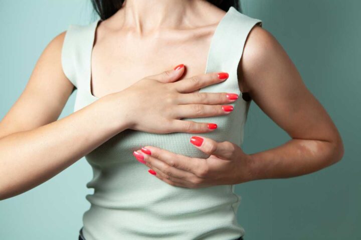 a young woman supporting her breasts from sagging with her hands